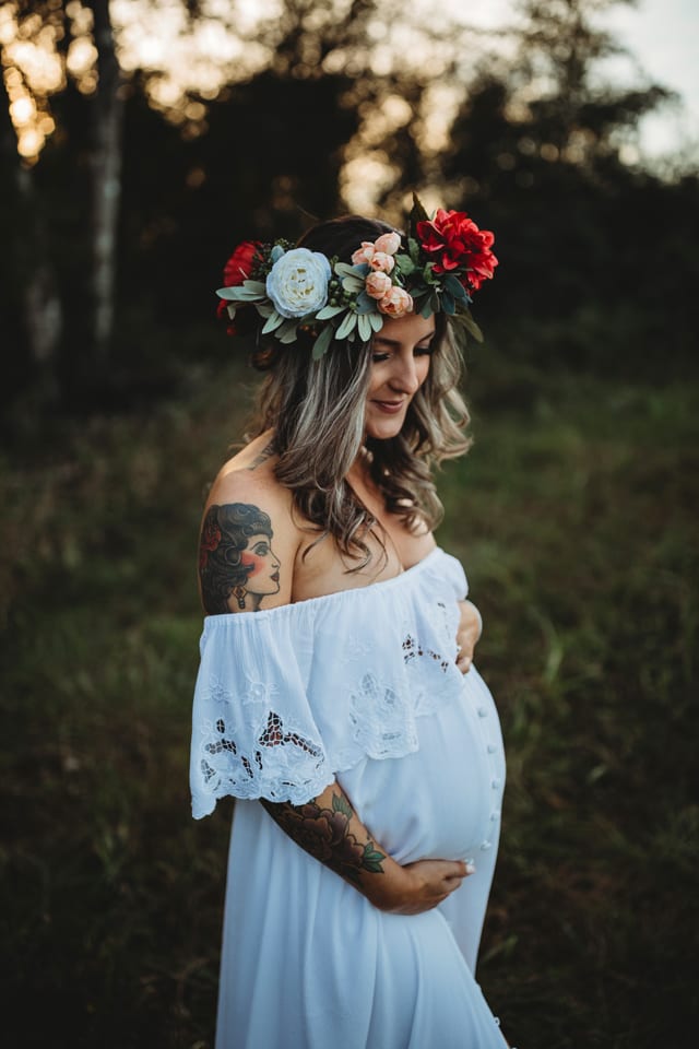 white dress maternity photo in the woods at sunset